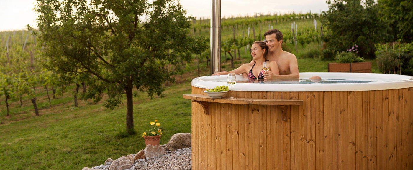Un couple assis dans le bain Rojal Skargards dans un jardin à côté des vignes.