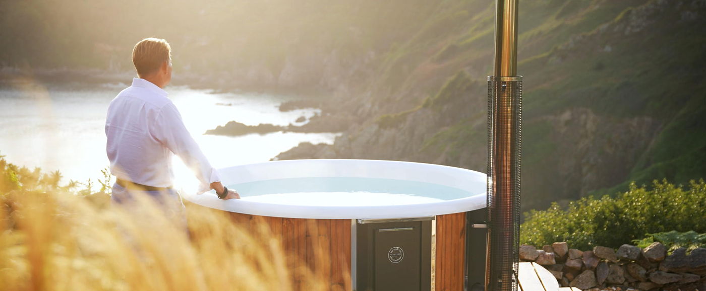 A man is standing next to the Hot Tub and has his hand on it