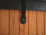 A black leather strap with holder on a wooden wall.