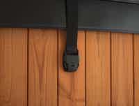 A black leather strap with holder on a wooden wall.