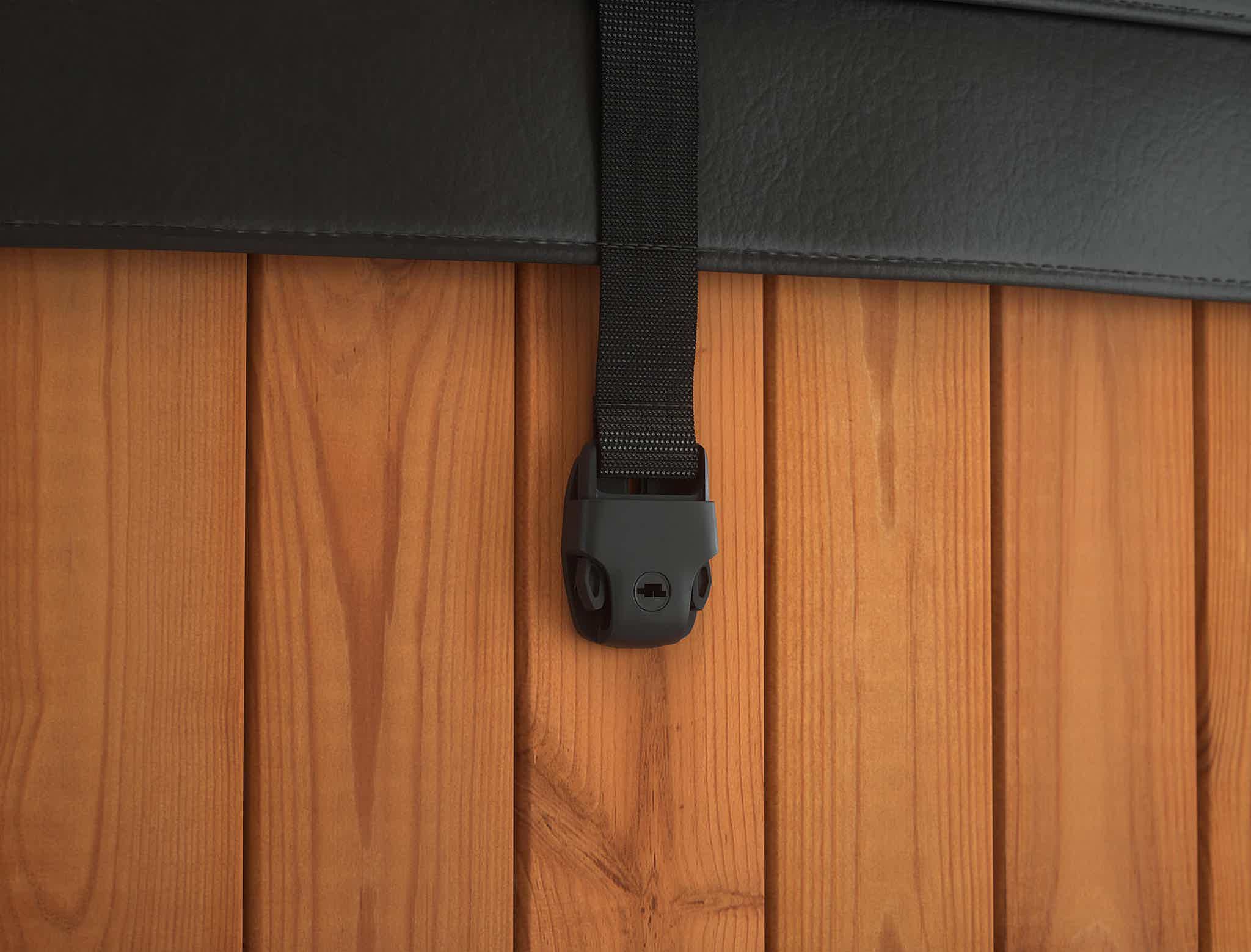 A black leather strap with holder on a wooden wall.