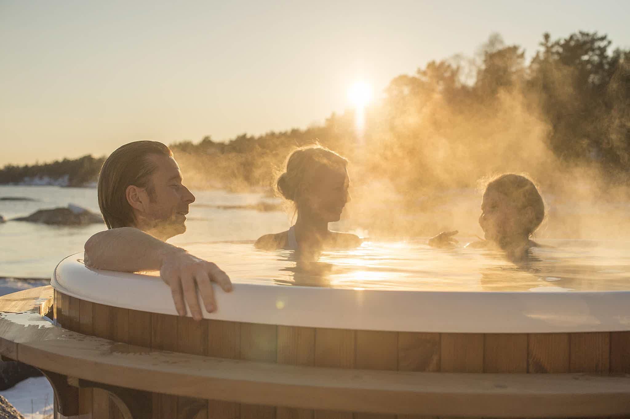 A family relaxes in a Skargards hot tub during winter, surrounded by nature.
