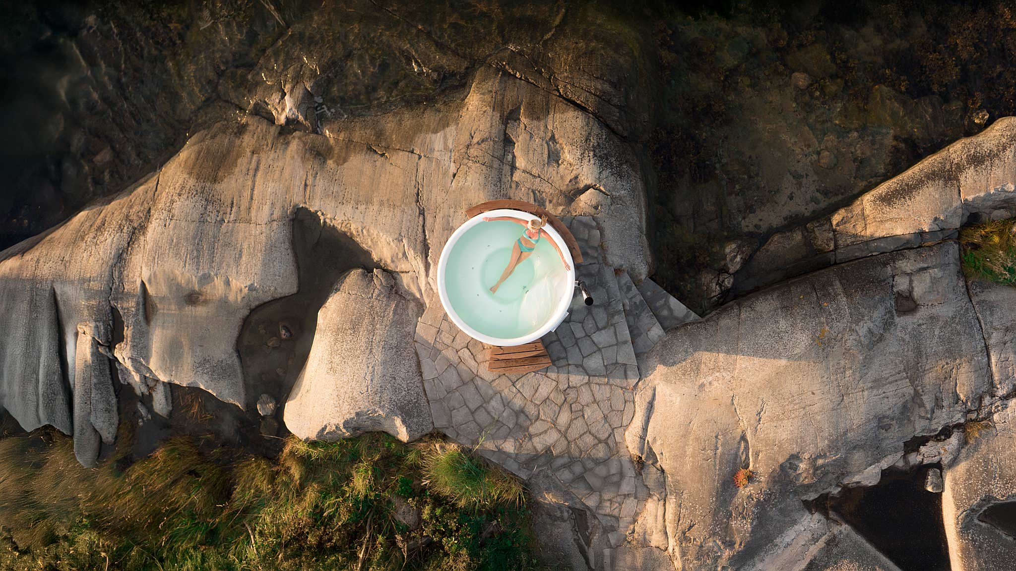 A Skargards Regal hot tub on a rocky landscape with greenery.
