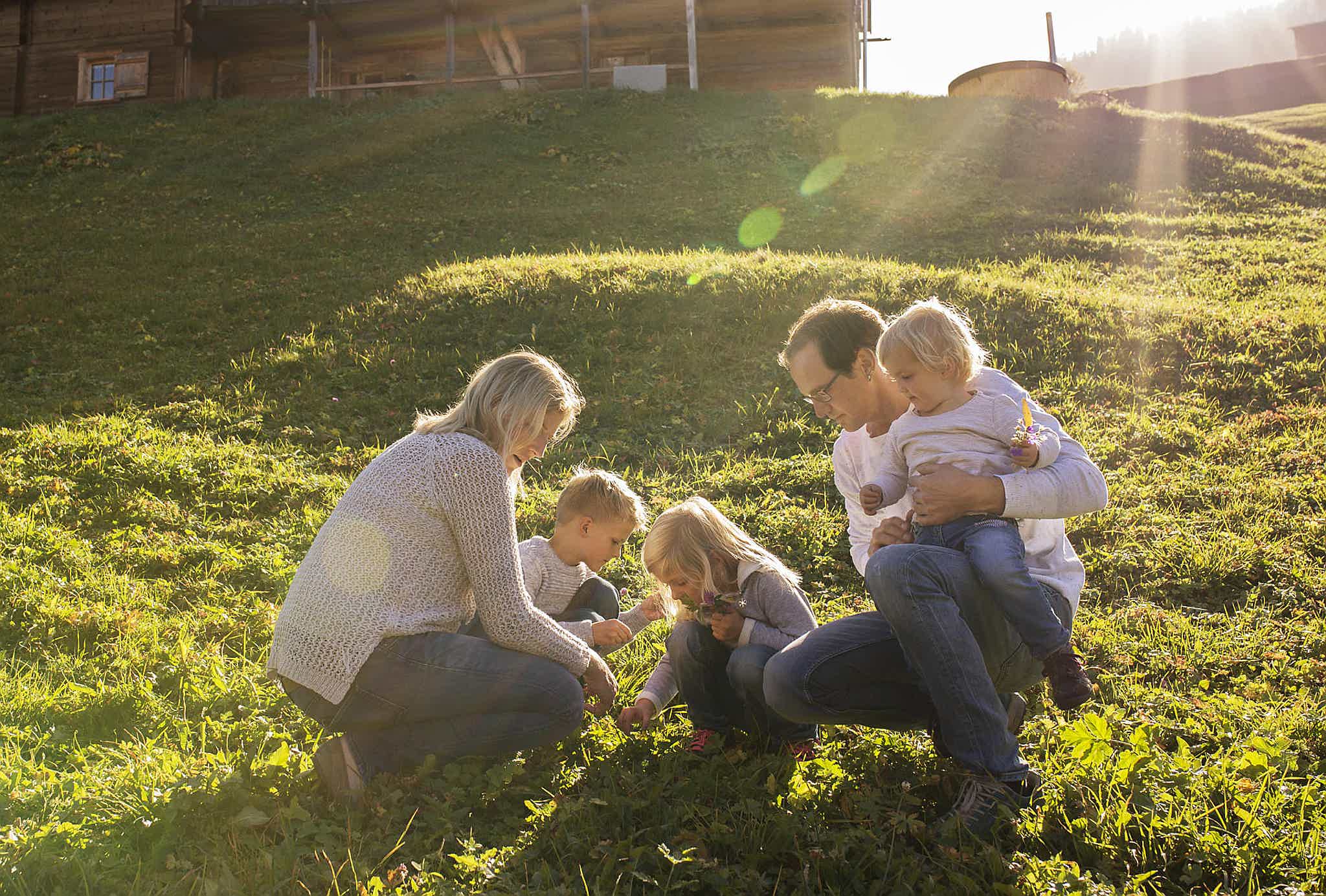 A family enjoying time together in a sunny field, a Skargards Regal hot tub in the background.