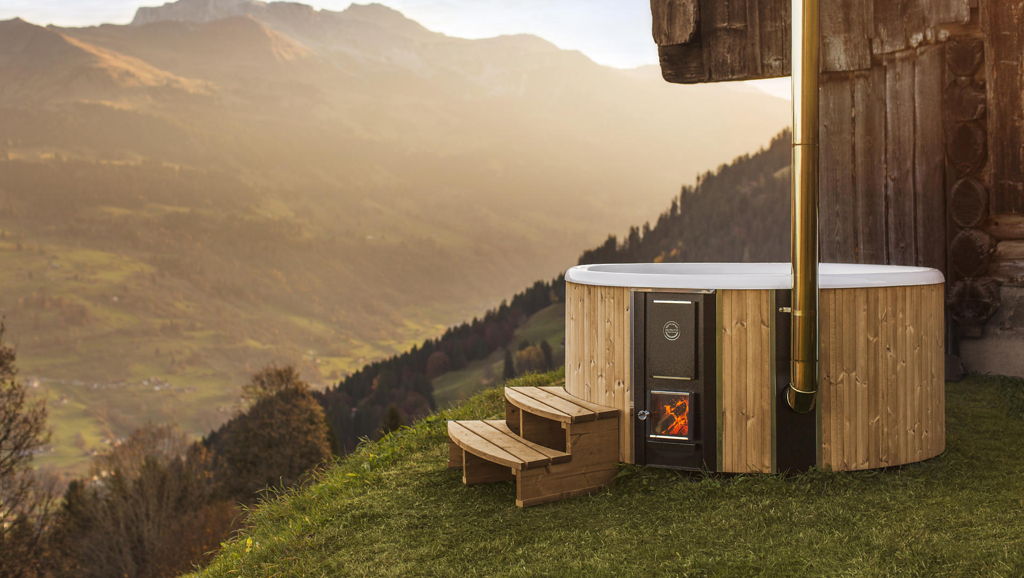 The Skargards Regal wood-burning hot tub placed next wo a wooden house in the Switzerland mountains