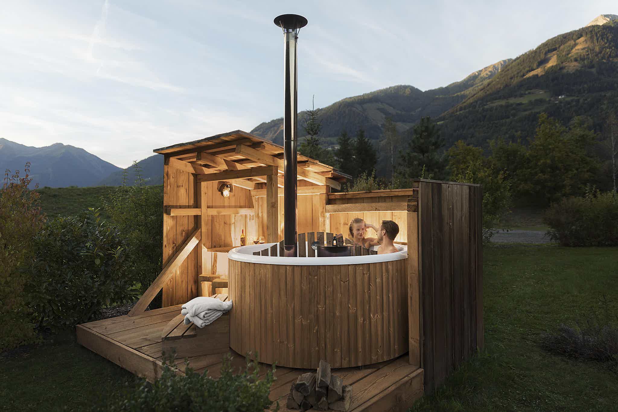 A couple enjoys a Skargards Panel 190 at Landgut Moserhof in the late noon, with mountains lit in sunset light.