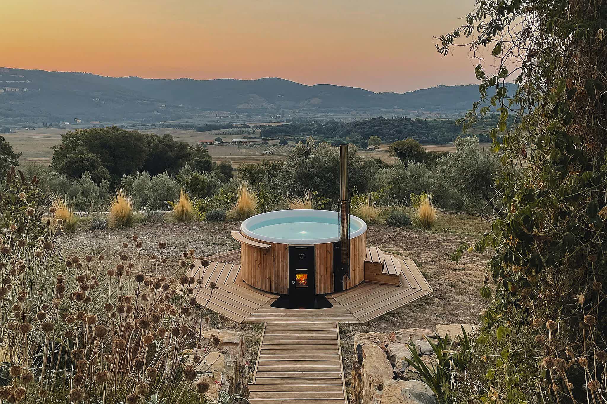 A Skargards Regal DualBurn 220 hot tub on a platform at sunrise in Tuscany's nature.