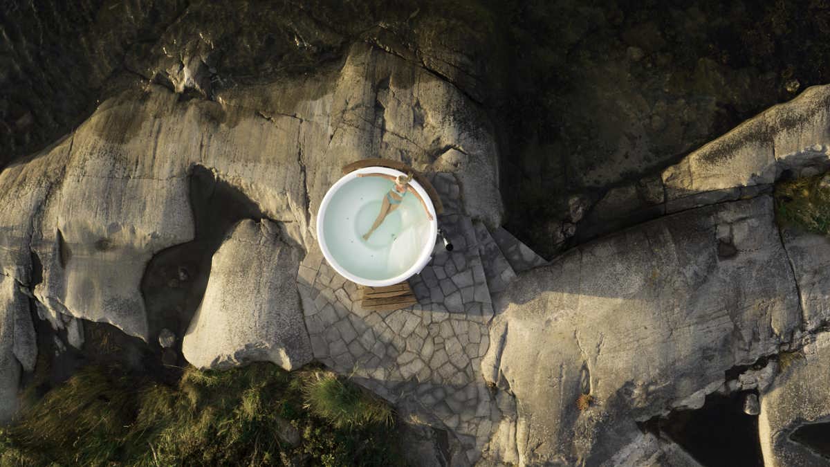 Aerial view of a Skargards Regal hot tub on a rocky shore, surrounded by nature.