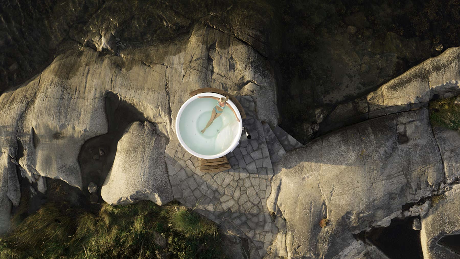 Aerial view of a Skargards Regal hot tub on a rocky shore, surrounded by nature.