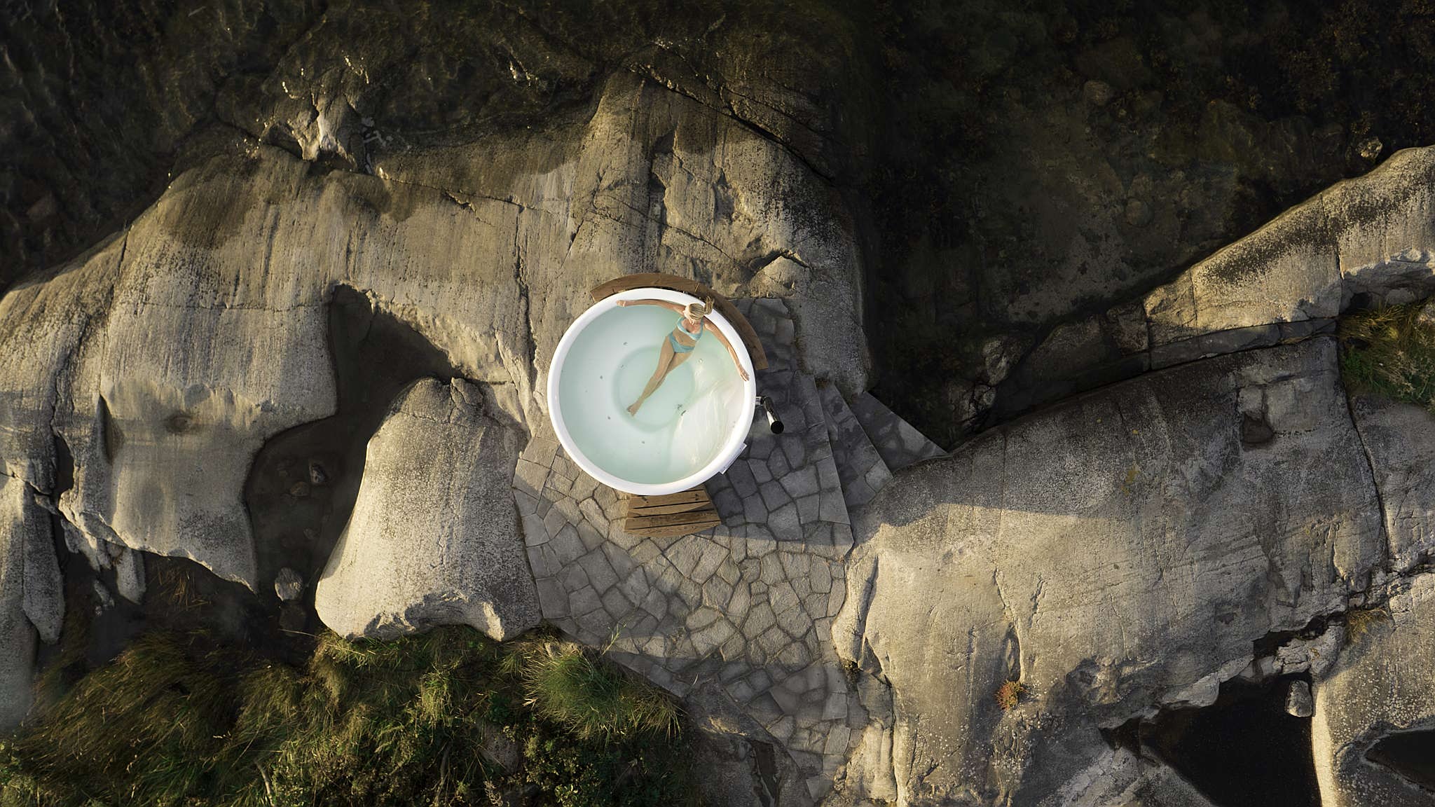 Aerial view of a Skargards Regal hot tub on a rocky shore, surrounded by nature.