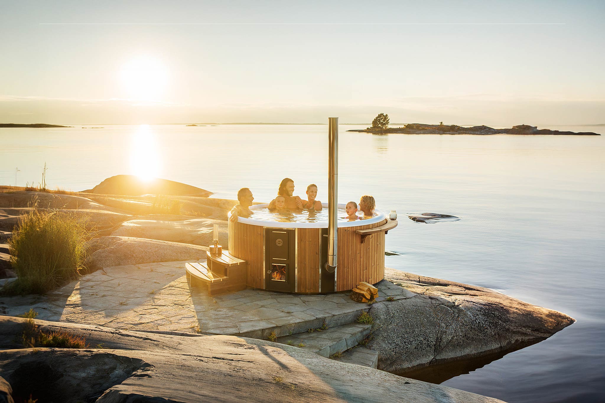 Skargards Regal hot tub on a rocky shore at sunset, creating a tranquil and relaxing atmosphere.