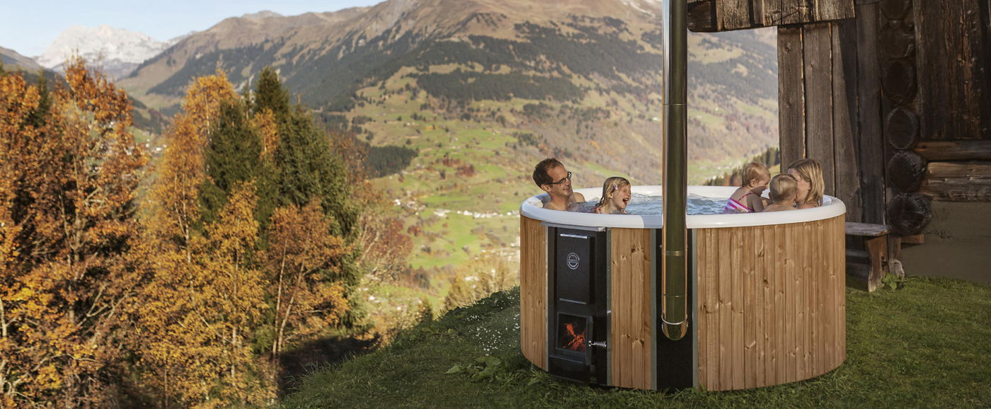 En familie nyter et bad i Skargards Regal vedfyrt badestamp plast i de sveitsiske fjellene