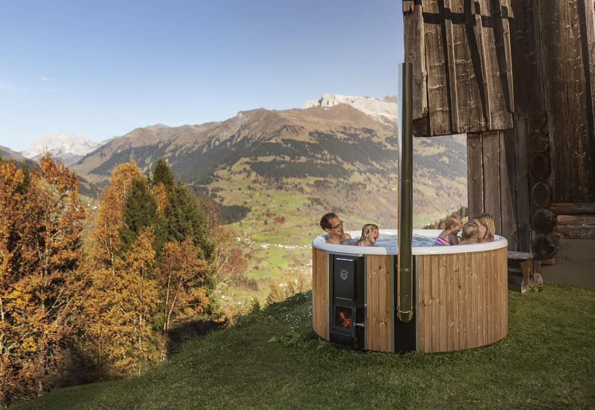A family enjoys a Skargards Regal hot tub in a alpine mountain setting.