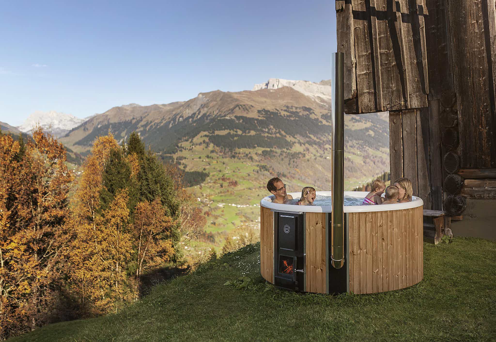 A family enjoys a Skargards Regal hot tub in a alpine mountain setting.