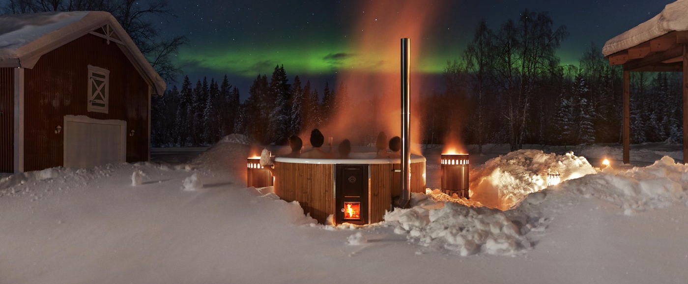 Un groupe de gens assis dans le bain scandinave Rojal en hiver regardant les aurores boréales