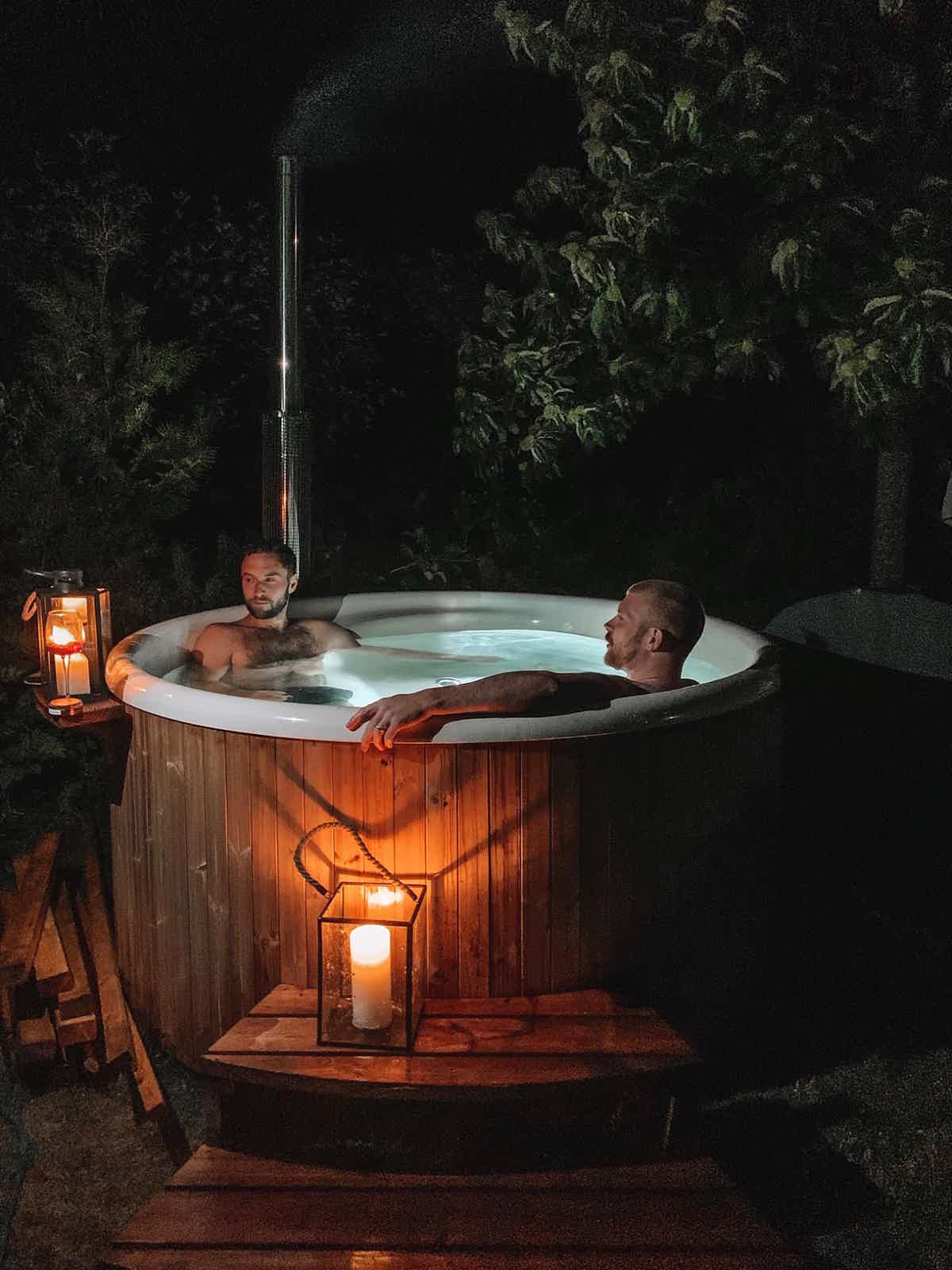 Måns Zelmerlöw and friend enjoy his Skargards Regal 190 hot tub on a deck, lit by candles, creating a serene mood.