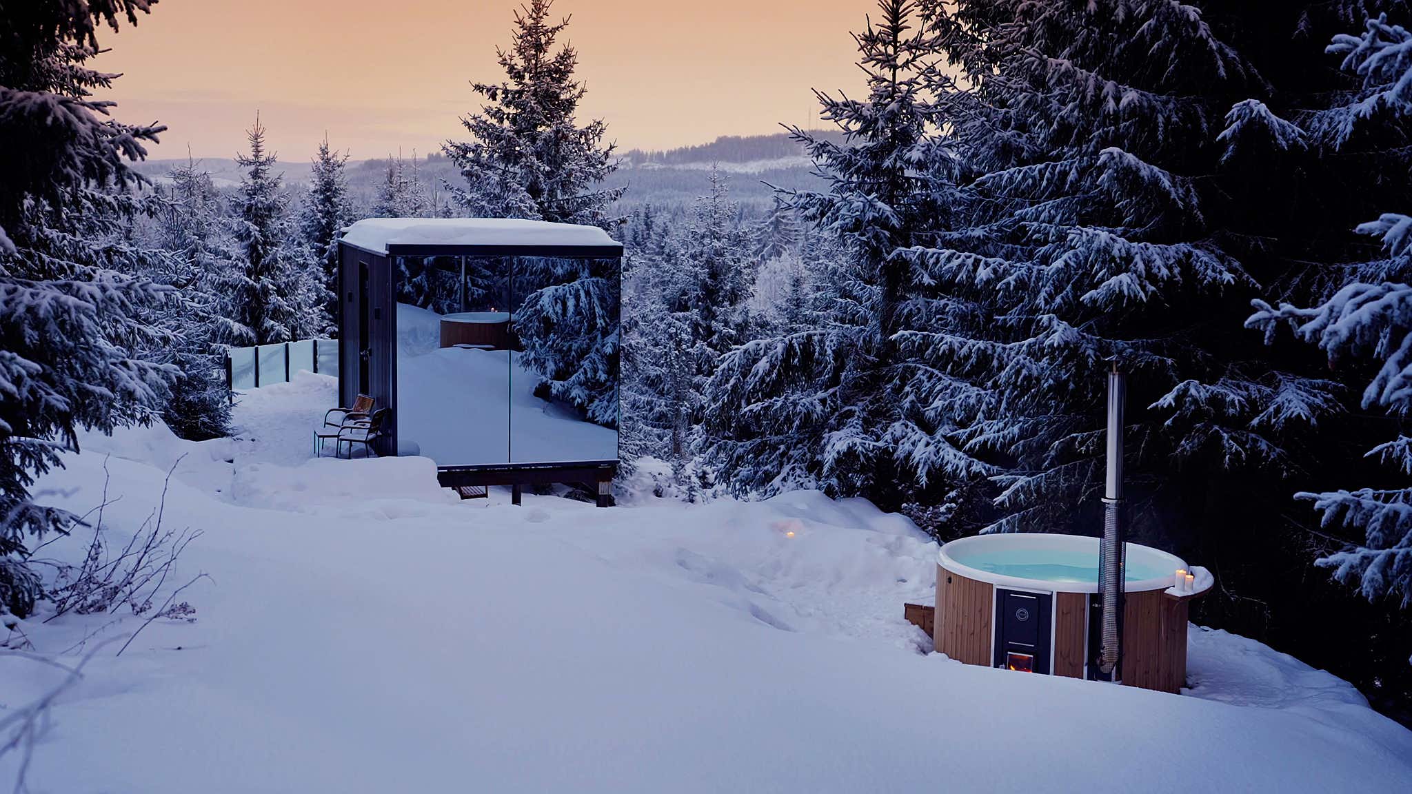 A Skargards hot tub in a snowy forest, offering a warm escape in a serene winter setting.