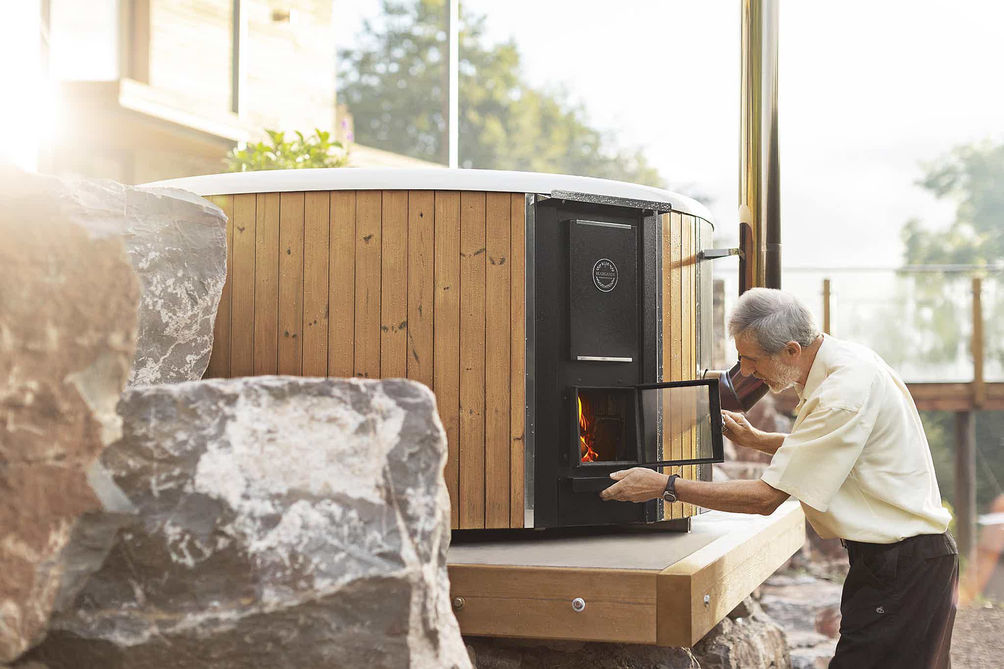 Hugh heats up the stove of his Skargards Regal DualBurn 190 hot tub on a terrace between rocks.