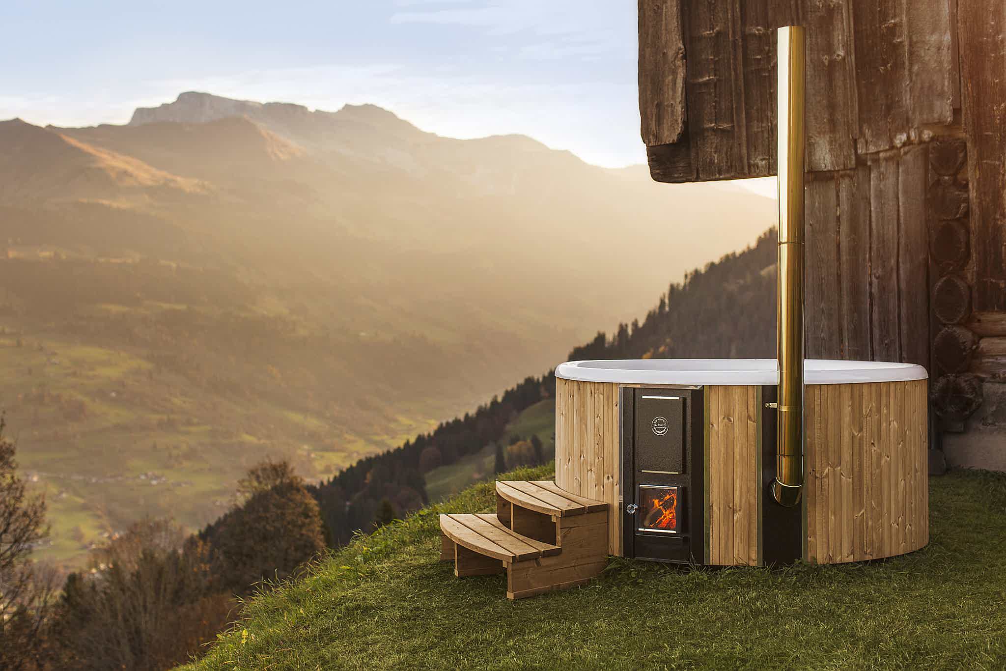 A wood-fired Skargards Regal DualBurn 190 hot tub overlooking a valley in the Swiss alps.