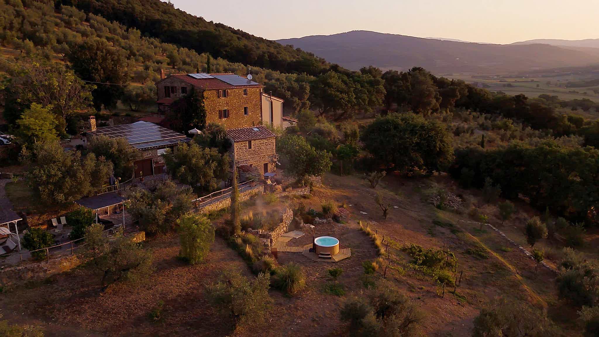 A Skargards Regal hot tub on a patio at Schiaccia Ghiande with lush greenery and mountains in the background.