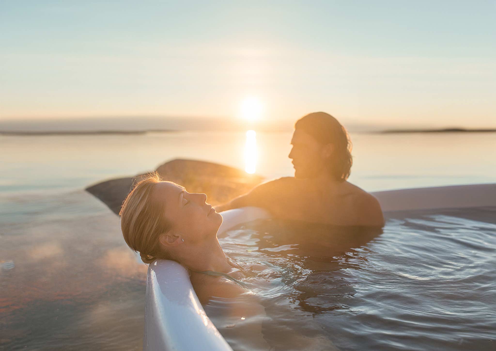 Couple relaxing in a Skargards Regal hot tub at sunset, enjoying the serene atmosphere.