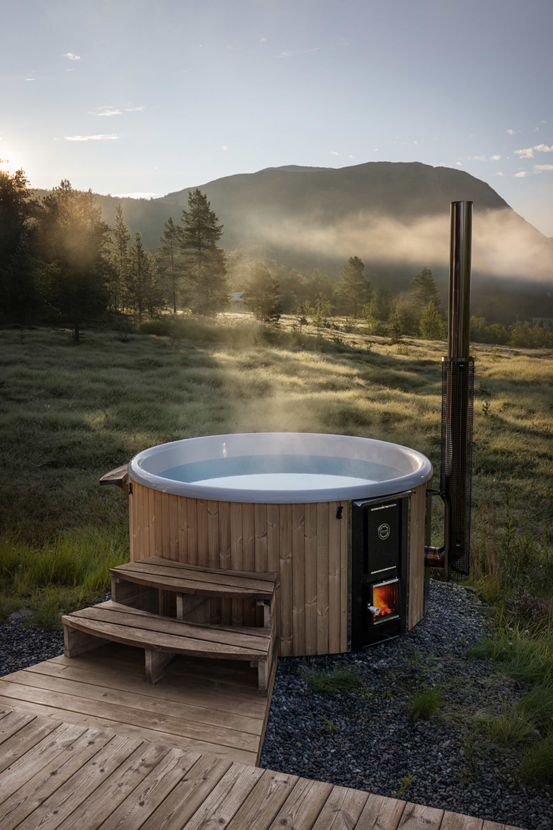 Luxurious hot tub on deck with mountain view, surrounded by nature.