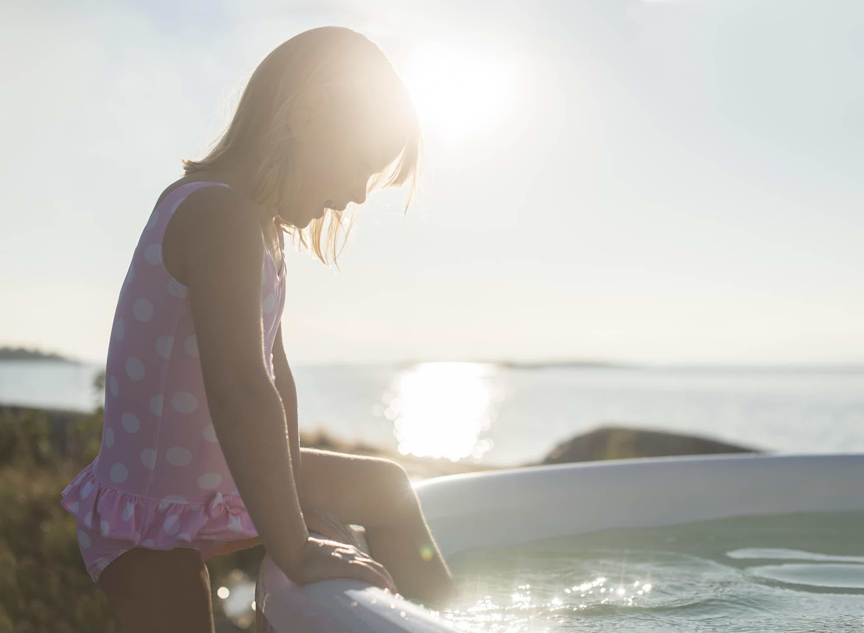 A girl steps into a Skargards Regal hot tub, surrounded by nature.