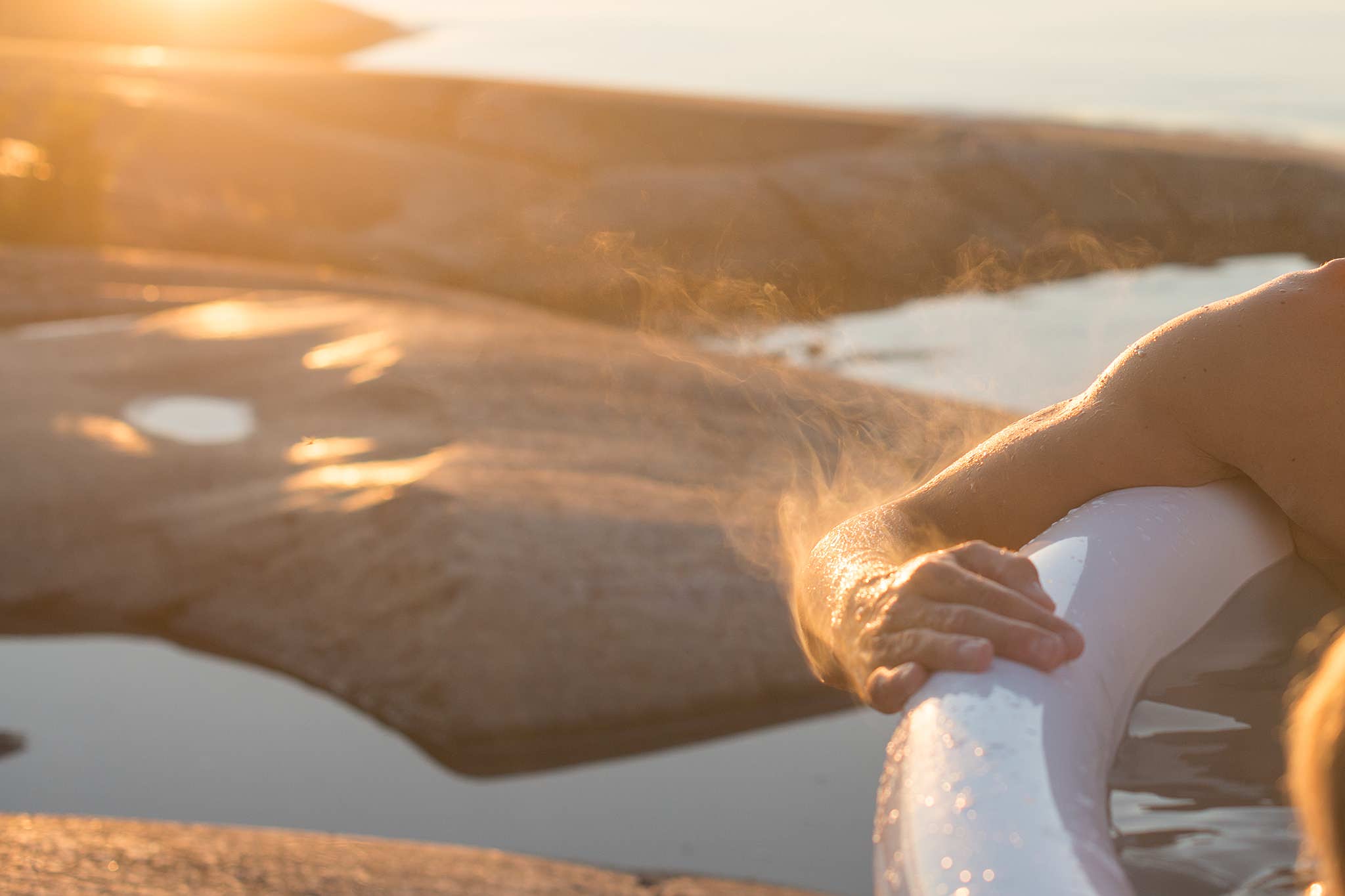 A person relaxes in a white inflatable pool at sunset.