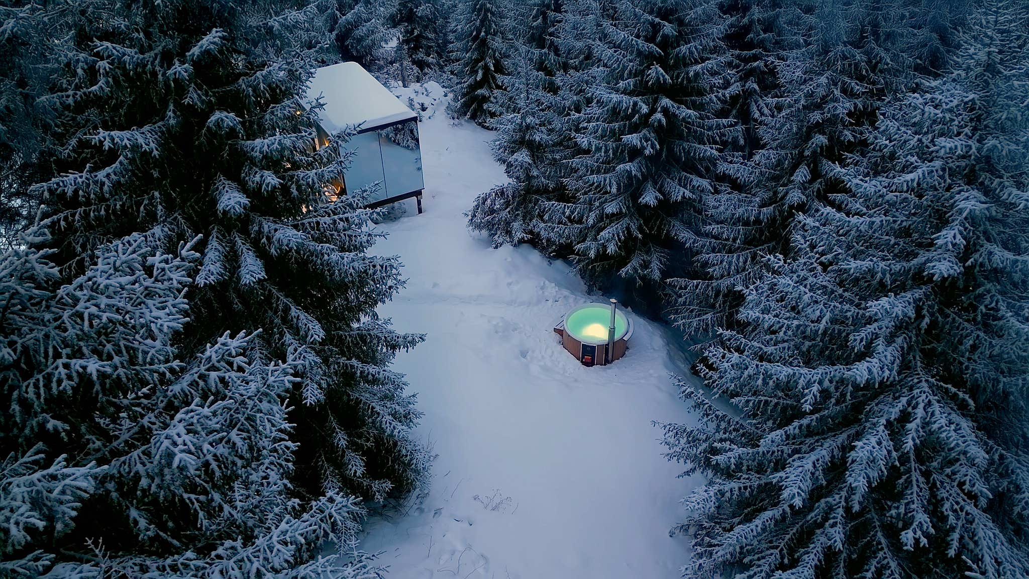 A Skargards hot tub in a snowy forest, creating a cozy winter retreat.