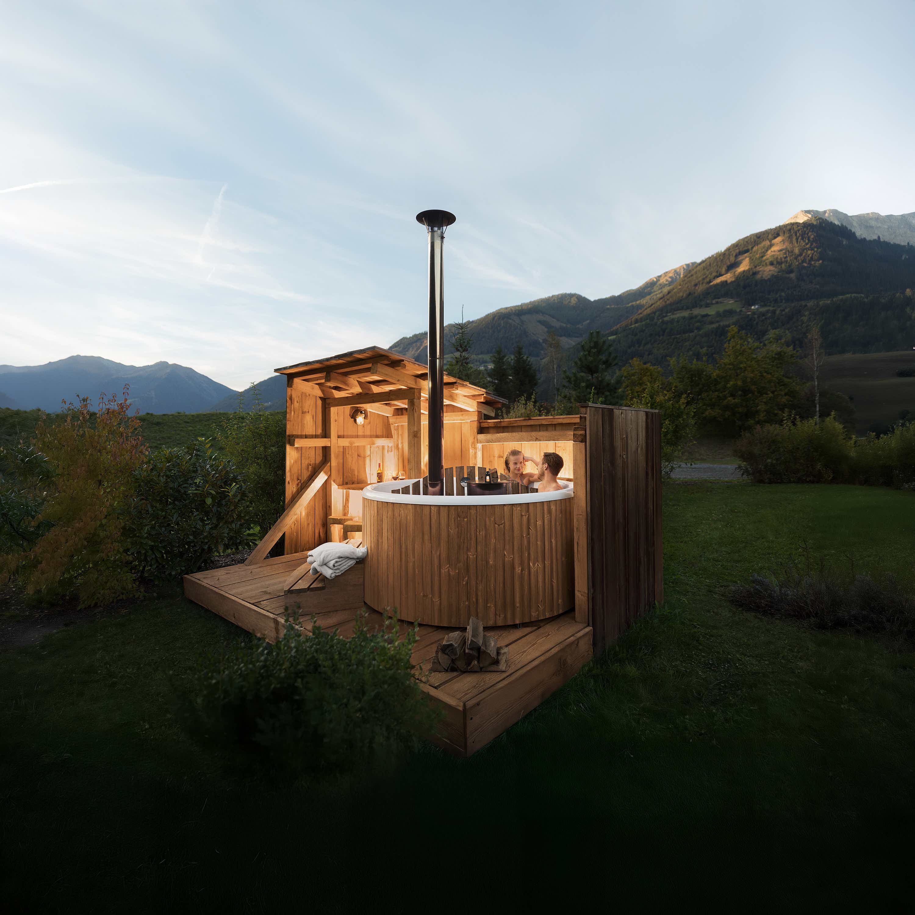 Luxurious wooden hot tub in a lush backyard with mountain view, creating a tranquil atmosphere.