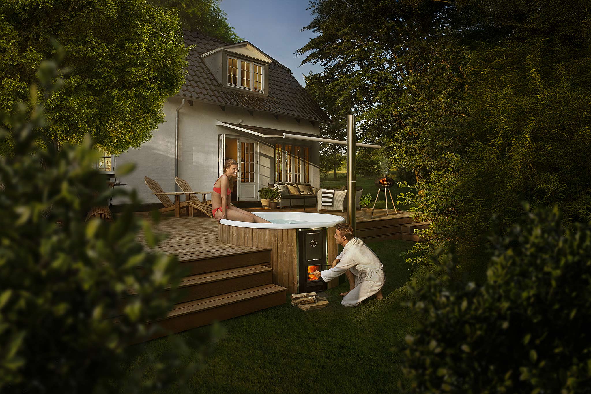 A couple enjoys a sunny afternoon on a wooden terrace with a Skargards Regal hot tub nearby.