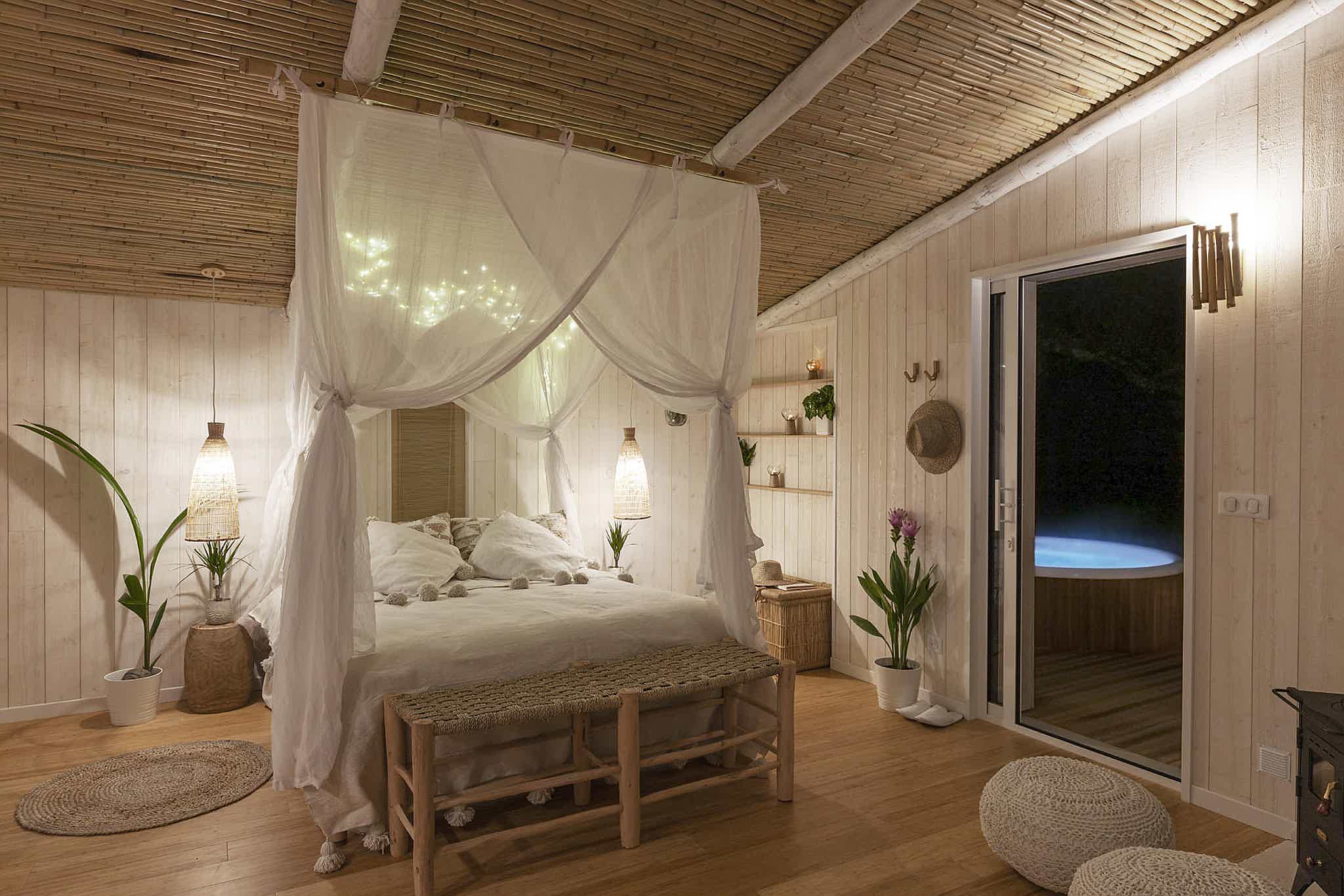 A serene bedroom with a canopy bed, wooden nightstands, and a sliding door leading to a Skargards hot tub.