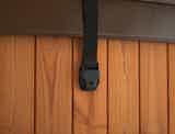 A leather strap with a black holder attached to a wooden wall.