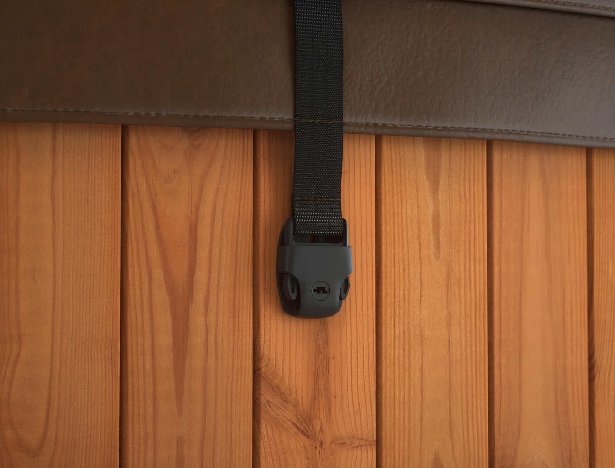 A leather strap with a black holder attached to a wooden wall.